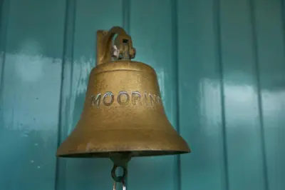 an old bell is hanging on a blue wall at The Moorings, overlooking Loch Fyne in Cairndow