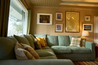 a living room with a blue couch and a window at The Moorings, overlooking Loch Fyne in Cairndow