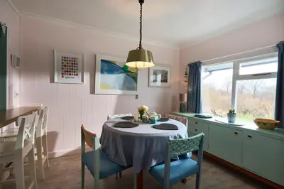 a dining room with a table and chairs and a window at The Moorings, overlooking Loch Fyne in Cairndow