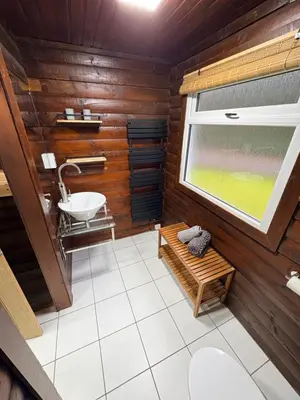 a bathroom with wooden walls and a sink and a window at Antler Lodge Traditional Log Cabin in Dunoon