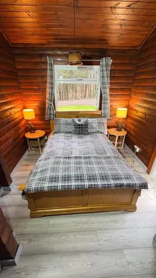 a large bed in a wooden room with two lamps at Antler Lodge Traditional Log Cabin in Dunoon