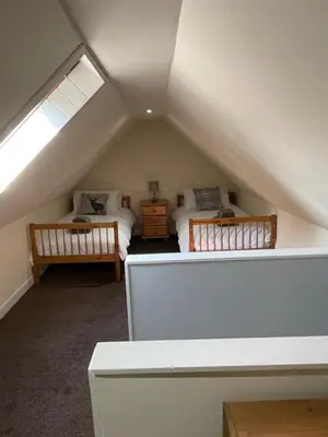 a attic room with two beds and a window at 1-2 Dialknowe Holiday Cottage - Wanlockhead in Wanlockhead