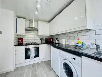 a kitchen with white cabinets and a washer and dryer at Central Hamilton House in Hamilton