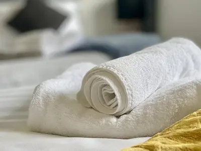 a roll of white towels sitting on a bed at Central Hamilton House in Hamilton