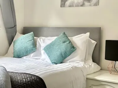 a bed with white sheets and blue pillows at Central Hamilton House in Hamilton