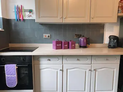 a kitchen counter with white cabinets and a purple appliance at MacLeen Cottage in Arrochar