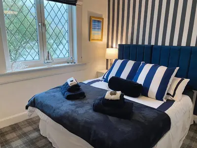 a bedroom with a blue and white bed with towels on it at MacLeen Cottage in Arrochar