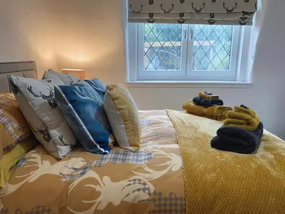 a bed with towels on top of it with a window at MacLeen Cottage in Arrochar