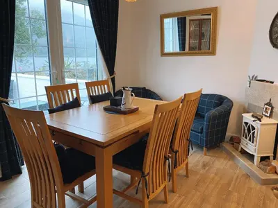 a dining room with a wooden table and chairs at MacLeen Cottage in Arrochar