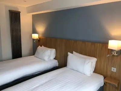 two beds with white pillows in a hotel room at Loch Lomond Hotel in Balloch
