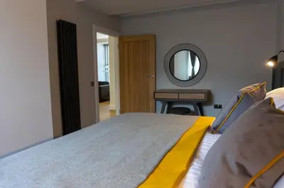 a bedroom with a large bed and a mirror at Argyle Square Apartment in Oban