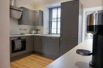 a kitchen with gray cabinets and a counter top at Argyle Square Apartment in Oban