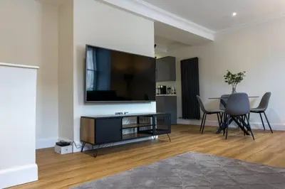 a living room with a tv and a table with chairs at Argyle Square Apartment in Oban