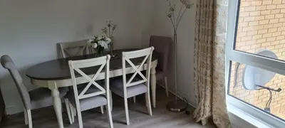 a dining room table with two chairs and a vase of flowers at Espedair Apartment in Paisley