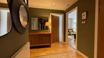 a hallway with a clock on the wall and a mirror at Glasgow Harbour Clyde Waterfront Apartment in Glasgow