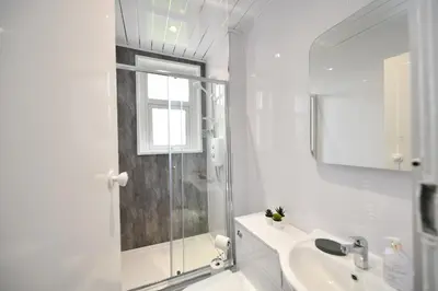 a white bathroom with a shower and a sink at Greensleeves Place in Troon