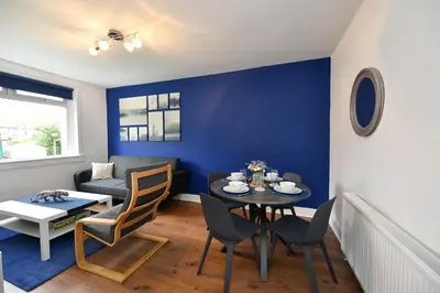 a living room with a table and chairs and a couch at Greensleeves Place in Troon