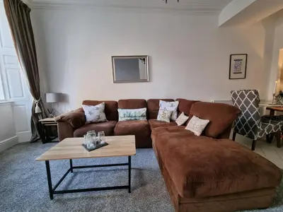 a living room with a brown couch and a table at Rose Apartment 2-Bed Apt Sleeps 4 Town Centre Ayr in Ayr