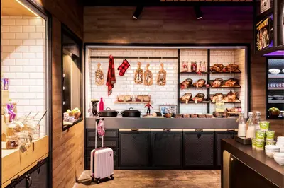 a bakery with a suitcase in front of a counter at Moxy Glasgow SEC in Glasgow