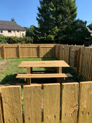 a wooden picnic table in front of a wooden fence at Woodvale Flat, Renton, Loch Lomond in Renton
