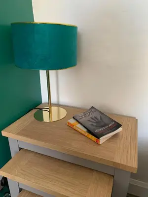 a lamp and a book on a table with a lamp and a lamp at Woodvale Flat, Renton, Loch Lomond in Renton