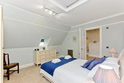 a white bedroom with a bed and a dresser at Luxury-3-bedroom Ramsay Garden Apartment next to Edinburgh Castle in Edinburgh