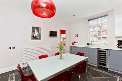 a kitchen with a white table and red chairs at Luxury-3-bedroom Ramsay Garden Apartment next to Edinburgh Castle in Edinburgh