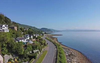 a view of a road and houses next to the water at Arthur's Seat in Innellan