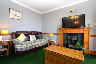 a living room with a couch and a flat screen tv at Arthur's Seat in Innellan