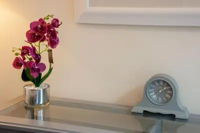 a vase of flowers on a glass table with a clock at Island View in Oban