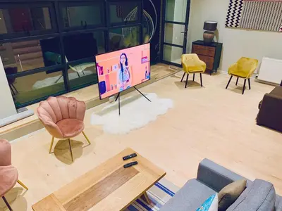 a living room with a flat screen tv and chairs at Glasgow City Centre G1 PENTHOUSE with RiverViews - Duplex - 4 Bedrooms, 3 Bathrooms, Kitchen, 1 Living room, 1 Dining room, 2 Terraces, Parking, Top Floor, 2050 sq ft, Merchant City in Glasgow