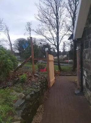 a wooden fence next to a brick walkway at Modernised 1720s cottage Newton Stewart Scotland in Newton Stewart