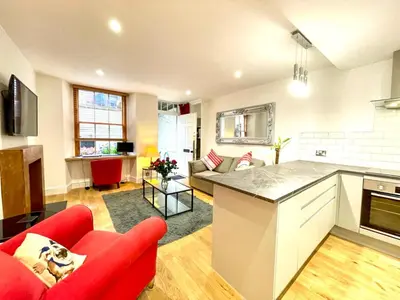 a kitchen and living room with a red couch at Prime Edinburgh New Town. Newly reno'd cosy nest in Edinburgh