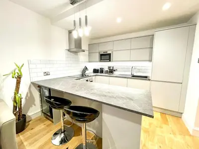 a white kitchen with a counter and two stools at Prime Edinburgh New Town. Newly reno'd cosy nest in Edinburgh