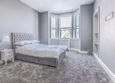 a white bedroom with a bed and a window at 4 Bed-Sleeps 8- Free Parking-Pets-Hot Tub in Kelty