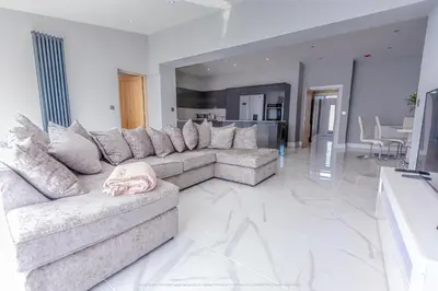 a large living room with a couch and a table at 4 Bed-Sleeps 8- Free Parking-Pets-Hot Tub in Kelty