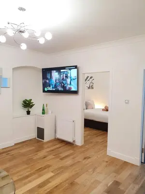 a living room with a bed and a flat screen tv on the wall at Glasgow Comfortable and Modern 3 Bedroom Mid Terraced Villa in Glasgow