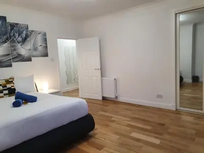 a white bedroom with a bed and a mirror at Glasgow Comfortable and Modern 3 Bedroom Mid Terraced Villa in Glasgow