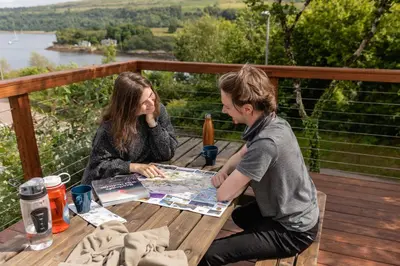 a man and woman sitting at a table with a map at Highland Basecamp in Lochaline