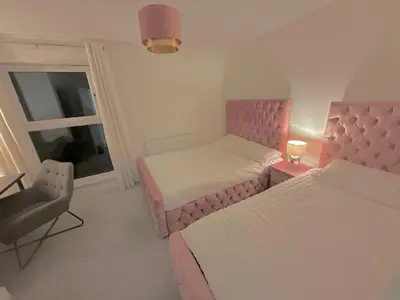 a bedroom with two beds and a chair and a window at Glasgow City Central Executive Triplex House, 3 Bedroom 3 Bathrooms 1 living room Kitchen - Huge Terrace for Master Bedroom - Private E Parking LEZ Congestion Zone Free - Garden - 5 mins drive to City Centre Central Station in Glasgow