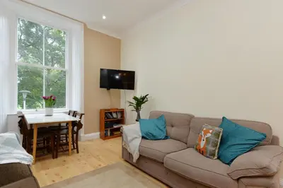 a living room with a couch and a table at Home by The Meadows, close to City Centre in Edinburgh