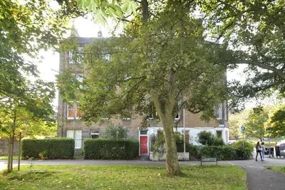 a tree in a park in front of a building at Home by The Meadows, close to City Centre in Edinburgh