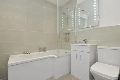 a bathroom with a toilet and a tub and a sink at Home by The Meadows, close to City Centre in Edinburgh