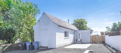 a small white house with two trash cans at 1 Bed Cottage-Sleeps 2-Parking-Pets-Hot Tub in Kelty