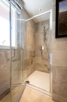 a shower with a glass door in a bathroom at Portnellan in Crianlarich