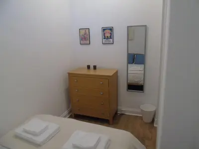 a bedroom with a bed and a dresser and a mirror at Snug - Tearlag Apartment in Helensburgh