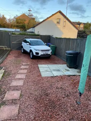 a white car parked in a yard next to a fence at Cheerful One bedroom cottage with parking space. in Glasgow