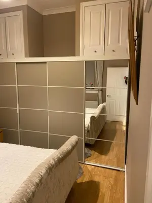a bedroom with a mirror next to a bed at Cheerful One bedroom cottage with parking space. in Glasgow