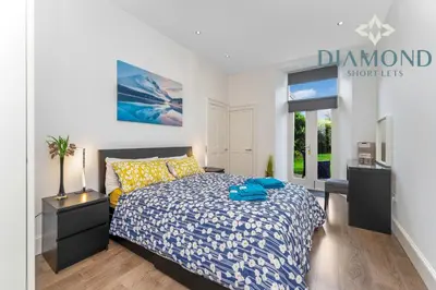 a bedroom with a bed and a desk and a window at Spacious 1 Bed Ground Floor Apartment with Garden in Edinburgh