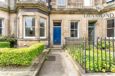a building with a blue door and a fence at Spacious 1 Bed Ground Floor Apartment with Garden in Edinburgh